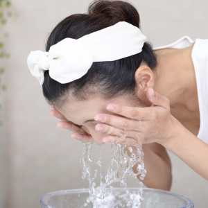 Mulher lavando o rosto para hidratar a pele